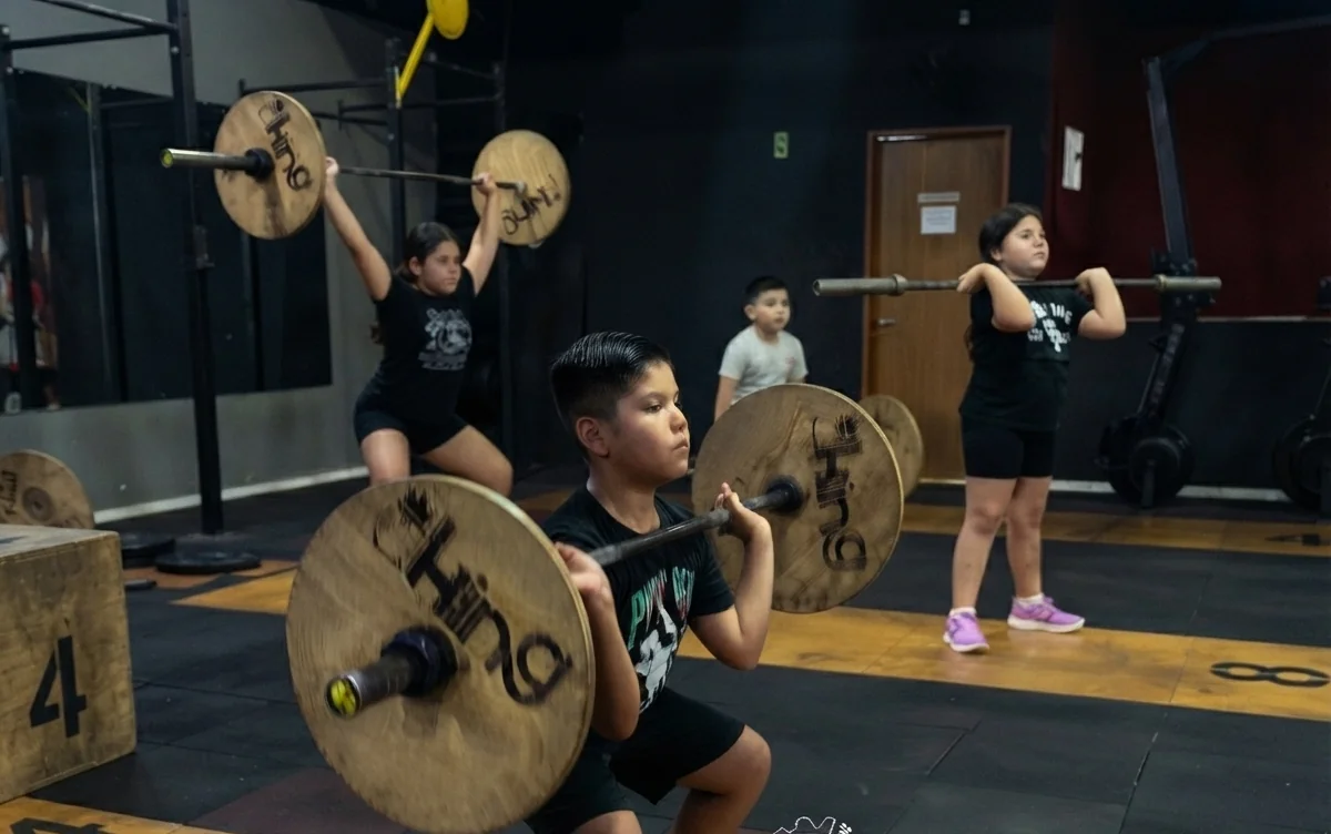 Crianças fazendo agachamento com barra no Funcional Kids