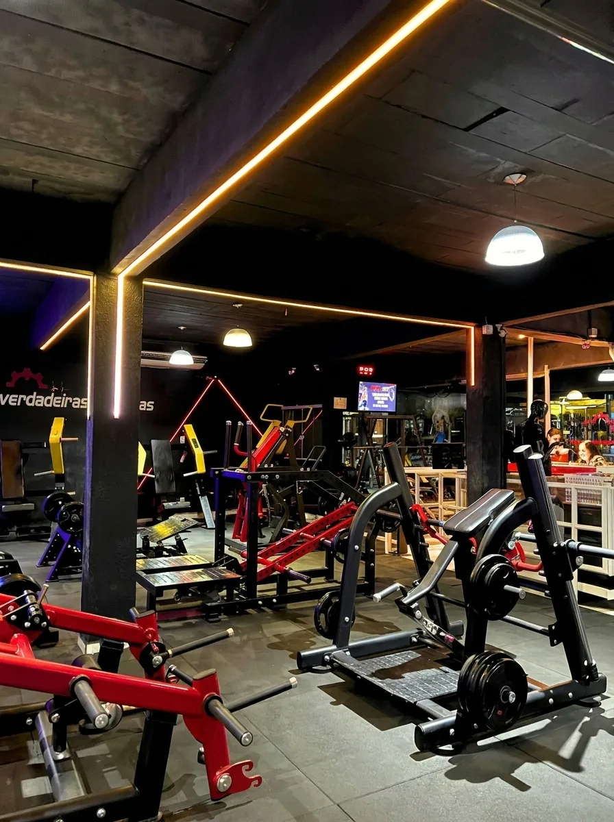 Máquinas de musculação vermelhas e pretas sob luz de LED