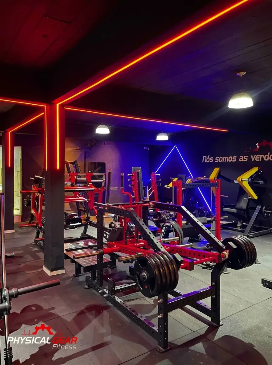 Salão de musculação com máquinas vermelhas e o mural Nós somos as verdadeiras máquinas